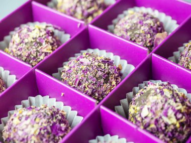 Mor bir kutunun içinde kurumuş gül yaprakları serpiştirilmiş şekerlemelerin ortasında odaklanmış yakın plan bir fotoğraf.