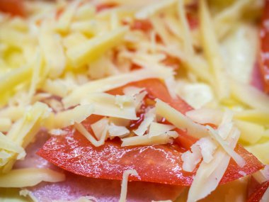 Bir dilim olgun kırmızı domates rendelenmiş peynir serpiştirilmiş.