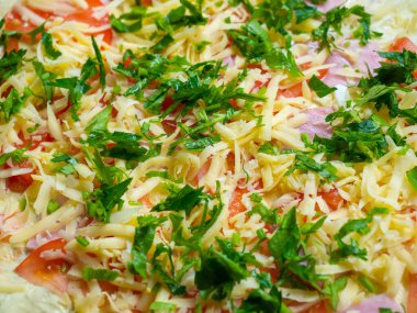 Jambon dilimleri, rendelenmiş domates ve taze otlarla pişirmek için hazırlanmış bir yemek.