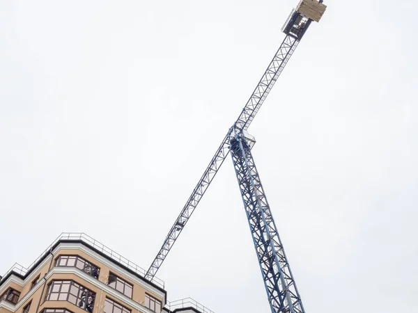 Grúa torre azul para la construcción de casas sobre un fondo nublado cerca de la parte superior de una casa nueva — Foto de Stock