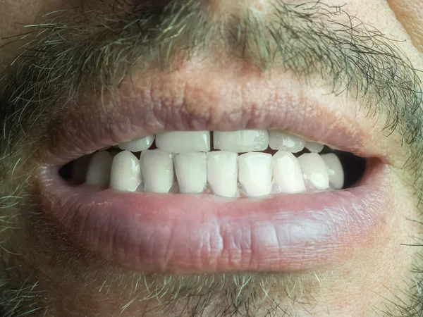 Fragment of a male face with a slightly open mouth and white teeth