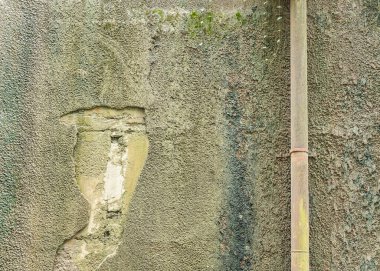 Demir paslı borusu olan eski beton duvar.