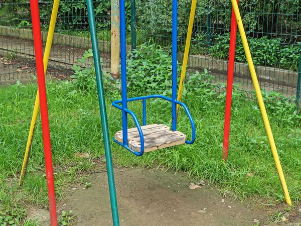 Altalena colorata per bambini nel parco giochi su erba verde — Foto Stock