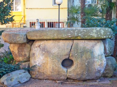 Dolmen, modern evlerin arka planında taş bloklardan oluşan tarihi bir simgedir.