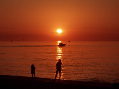 Anne ve kızı iskeleden gün batımını seyrediyor.