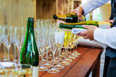 Číšník nalil osobní servírování šampaňského v brýlích. Cateringové služby v události, firemní setkání, párty, svatby. Selektivní fokus, prostor pro text