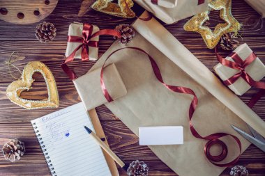 Üstten Görünüm tatil dekorasyon ve defter hediyeler düz yatıyordu tarzı ahşap rustik masada listesi ile. Noel planlama kavramı. Seçici odak. Metin için yer. Vintage tonlama.