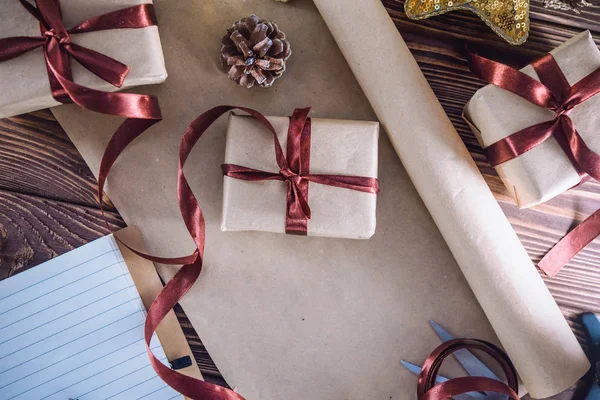 Top view Holiday decorations and packaged gifts, notebook on wooden rustic table, flat lay style. Christmas planning concept. Selective focus. Space for text — Stock Photo, Image