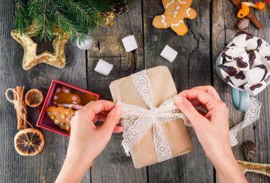 Hediye gingerbred kurabiye ile ahşap masa vintage dantel kurdele ile dekorasyon üstten görünüm eller, dekor, fincan kakao ile murshmellows ile Noel ağacı dalları. Seçici odak.