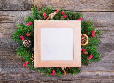 Noel çelenk ile doğal dekorasyon - çilek, koniler, şekerlenmiş portakal, tarçın, anason kopya alanı içinde kare çerçeveli boş kağıt kartı. Eski rustik ahşap arka plan.