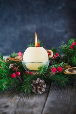 Yuvarlak Fildişi yanan Noel mum Noel çelenk koyu taş arka plan ile eski rustik tabloda doğal dekor ile kapatın. Noel şenlikli kavramı. Seçici odak. Metin için yer
