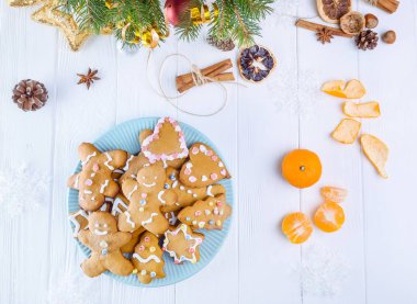 Ev yapımı gingerbread çerezleri çam dalları dekorasyon, çam kozalağı, baharat, mandalina, drided portakal ile beyaz ahşap tablo ile plaka mavi. Noel şenlikli arka plan, seçici odak