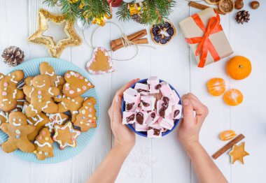 Üstten Görünüm kadın murshmellows hediye kutusu, gingerbred tanımlama bilgilerini, Noel ağaç dalları, dekor, baharat, mandalina ahşap tablo ile sıcak kakao fincan holding eller. Seçici odak. Metin alanı