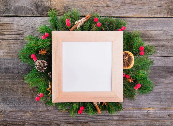 Noel çelenk ile doğal dekorasyon - çilek, koniler, şekerlenmiş portakal, tarçın, anason kopya alanı içinde kare çerçeveli boş kağıt kartı. Eski rustik ahşap arka plan.