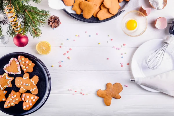 Beyaz ahşap masa, Noel arka plan kavramı üzerinde Noel ev yapımı gingerbread çerezleri. Beze krema ile dekorasyon işlemi. Seçici odak. Metin, en iyi görünüm için yer