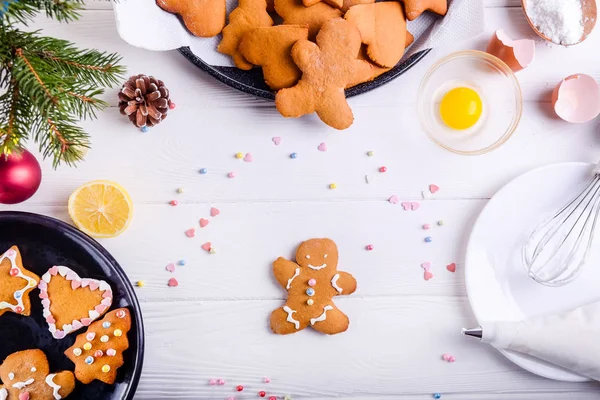 Beyaz ahşap masa, Noel arka plan kavramı üzerinde Noel ev yapımı gingerbread çerezleri. Beze krema ile dekorasyon işlemi. Seçici odak. Metin, en iyi görünüm için yer