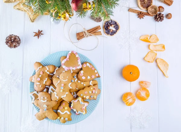 Ev yapımı gingerbread çerezleri çam dalları dekorasyon, çam kozalağı, baharat, mandalina, drided portakal ile beyaz ahşap tablo ile plaka mavi. Noel şenlikli arka plan, seçici odak