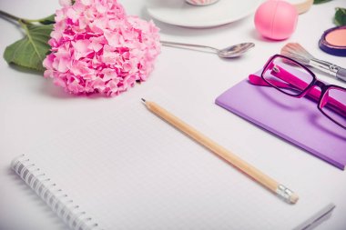 Üstten Görünüm kadın çalışma planlaması defter ile kozmetik yerleştirin, sketchbook, gözlük ve wisteria çiçek beyaz arka plan üzerinde. Moda, güzellik blog kavramı.