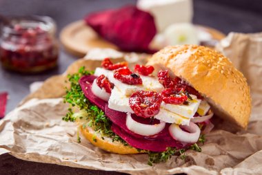 Pancar dilimleri, microgreen lahanası, tofu peyniri, kurutulmuş domates ve soğan kraft paket kağıt inhrediants karanlık taş zemin üzerine Vegitarian burger. Yumuşak seçici odak. Kopya alanı.