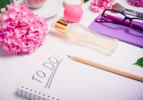 Lugar de trabajo femenino con Para hacer lista, accesorios cosméticos, cuaderno, gafas y flores de glicina en el fondo blanco. Planificación del día. Moda, concepto de blog de belleza . —  Fotos de Stock