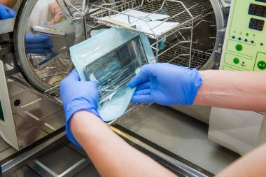 Dişçi asistanın eller yakından almak otoklav diş Office tıbbi aletleri sterilize et. Seçici odak