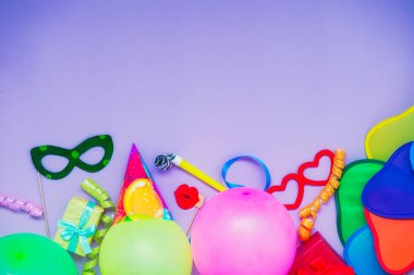Üstten Görünüm parlak parti araçları ve dekorasyon - baloons, komik karnaval maskeler, Lila zemin üzerine Festival gelin teli. Mutlu doğum günü tebrik kartı. Purim. Tasarım konsepti. Odağı seçin, metin için yer.