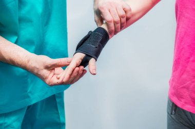 Nörolog Doktor, terapist koyar üzerinde bilek hizmetli genç kadın hastanın yandan kapatın. Ağrı tedavisi. Nöroloji, osteopati, chiropractic. Seçici odak. metin için yer.
