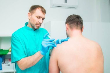 Nörolog doktor bir enjeksiyon tedavisi, abluka erkek hastanın deltoid kas içine yapıyor. Alternatif ağrı tedavi kavramı. Seçici odak, metin için yer.