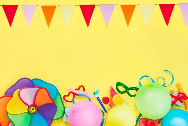 Amarillo brillante Fondo festivo con herramientas de fiesta y decoración: globos, máscaras de carnaval divertidas, oropel festivo y guirnalda con banderas. Feliz marco de cumpleaños. Concepto de diseño. Lugar para el texto . —  Fotos de Stock