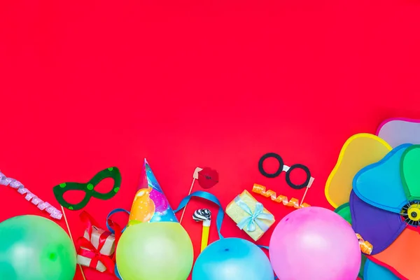 Rojo brillante Fondo festivo con herramientas de fiesta y decoración: globos, máscaras de carnaval divertidas, oropel festivo. Feliz cumpleaños tarjeta de felicitación. Concepto de diseño. Seleccionar enfoque, lugar para texto . —  Fotos de Stock