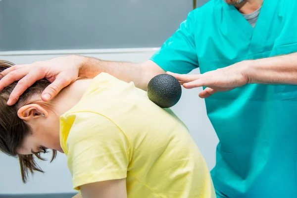 Mulher na fisioterapia recebendo massagem de bola do terapeuta. Um quiroprático trata a coluna torácica do paciente em consultório médico. Neurologia, osteopatia, quiropraxia. Foco seletivo, Fechar . — Fotografia de Stock