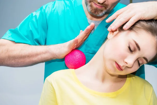 Kvinna på den sjukgymnastik som tar emot bollen massage från terapeuten. En kiropraktor behandlar patientens axel, nacke i medicinsk kontor. Neurologi, osteopati, kiropraktik. Selektiv fokus, närbild. — Stockfoto