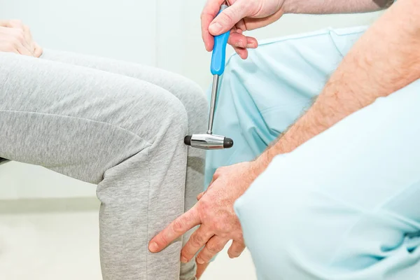 Η Νευρολόγος δοκιμών γόνατο αντανακλαστικό σε γυναίκα ασθενή χρησιμοποιώντας ένα σφυρί. Νευρολογική κλινική εξέταση. Επιλεκτική εστίαση, κοντινό πλάνο. — Φωτογραφία Αρχείου