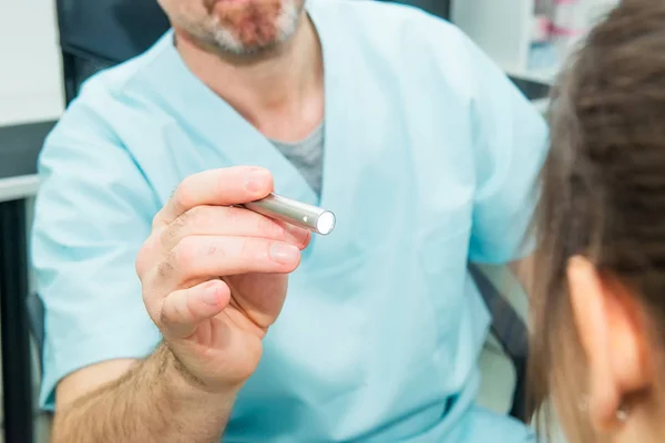 Close up médico testando reflexos do olho de mulher jovem usando uma lâmpada na clínica médica. Exame físico neurológico. Foco seletivo, espaço para texto . — Fotografia de Stock