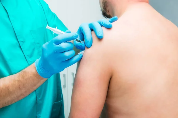 Close up O médico neurologista faz uma terapia de injeção (bloqueio) no músculo deltóide do paciente masculino. Conceito alternativo de tratamento da dor. Foco seletivo, espaço para texto . — Fotografia de Stock