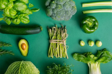 Yeşil arka planda sağIıklı çiğ sebzeler ve ahşap bloklarda Yeşili Ye mesajı. Vejetaryen ve vejetaryen diyeti. Vejetaryenlik kavramı. Sürdürülebilir yaşam tarzı, iyi, gerçek bitkisel gıdalar