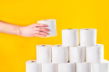 Beyaz erkek eli, parlak sarı arka planda katlanır rulo bir tuvalet kağıdı rulosu alır. Kriz ürünü eksikliği kavramı