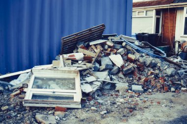 Özel evin yakınındaki inşaat atığı yığını. Molozlar, tuğlalar, taşlar. Çöpler binanın yakınına yığılmış. Sokak sahnesi. Geri dönüşüm endüstrisi, çöp temizleme ve toplama hizmeti