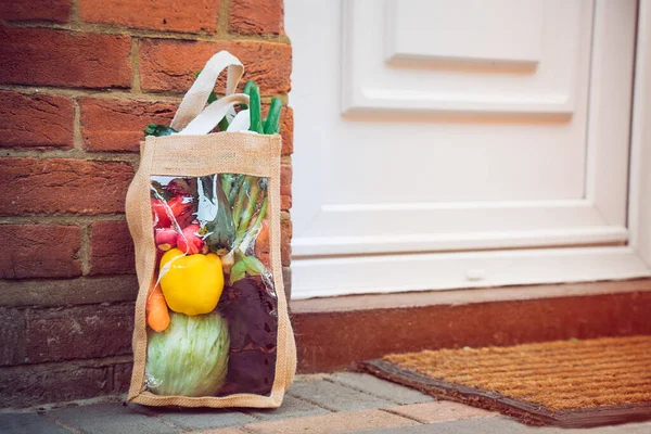 Fresh organic vegetable delivery concept. Reusable bio eco sackcloth fabric bag packaging near brick wall house threshold. Local farmer healthy food. Zero waste and plastic-free lifestyle. Copy space
