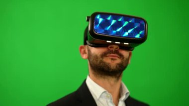 Takım elbiseli adam sanal gerçeklik gözlük kullanır. VR. yeşil arka plan. Sanal gerçeklik adamdır. Yüksek teknoloji ürünü cihazlar. Yeşil bir arka plan baş hareketi. Sanal gerçeklik kask. 4 k çözünürlük.