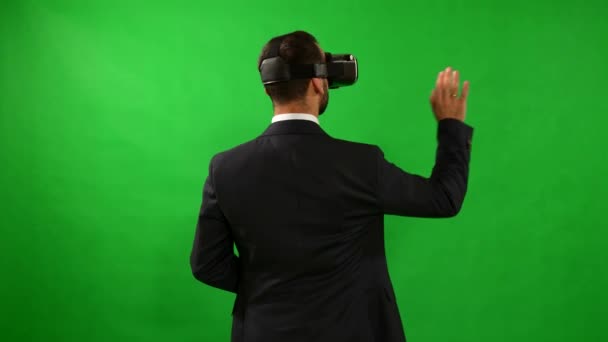 Man in suit uses virtual reality goggles. VR. Green background. A man uses virtual interface. High-tech devices. The movement of the hands on a green background. Virtual reality helmet. 4K resolution. — Stock Video