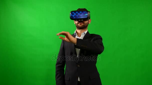 Hombre de traje usa gafas de realidad virtual. Fondo de VR. Green. Un hombre usa la interfaz virtual. Dispositivos de alta tecnología. El movimiento de las manos sobre un fondo verde. Casco de realidad virtual. resolución de 4 k. — Vídeos de Stock