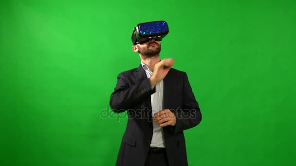 Hombre de traje usa gafas de realidad virtual. Fondo de VR. Green. Un hombre usa la interfaz virtual. Dispositivos de alta tecnología. El movimiento de las manos sobre un fondo verde. Casco de realidad virtual. resolución de 4 k. — Vídeos de Stock