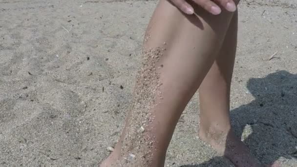 Mujer sacudiéndose de arena de las piernas en la playa — Vídeo de stock