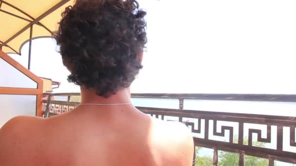 Ευτυχισμένος άνθρωπος χαλάρωση στο μπαλκόνι απολαύστε κοιτάζοντας γύρω από τις καλοκαιρινές του διακοπές — Αρχείο Βίντεο
