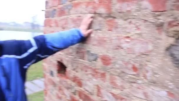 Mann blickt auf uralte Mauer, die sich von Hand berührt — Stockvideo