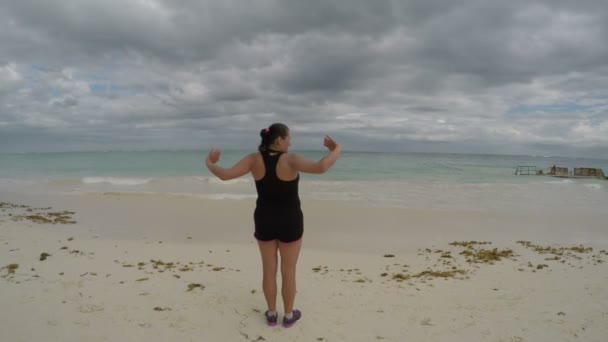 Женщина наслаждается видом на пляж и стретчинг — стоковое видео