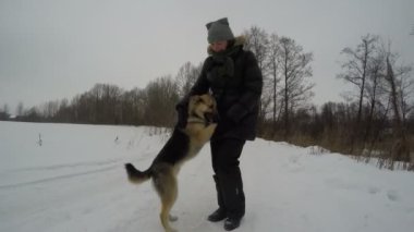 Çoban köpeği ile kış karda oynayan kadın