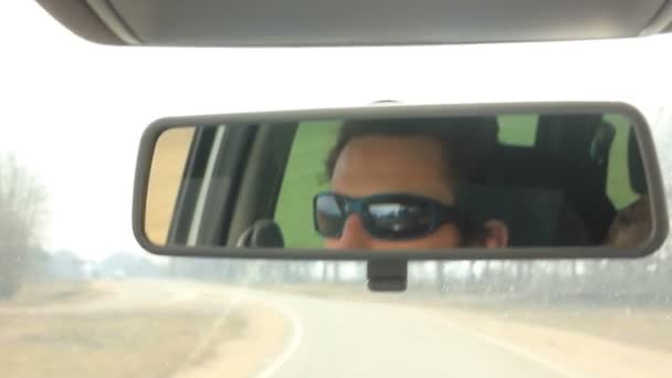 Ο άνθρωπος οδήγηση αυτοκινήτου βάζοντας κάτω καπάκι κατά του ήλιου — Αρχείο Βίντεο