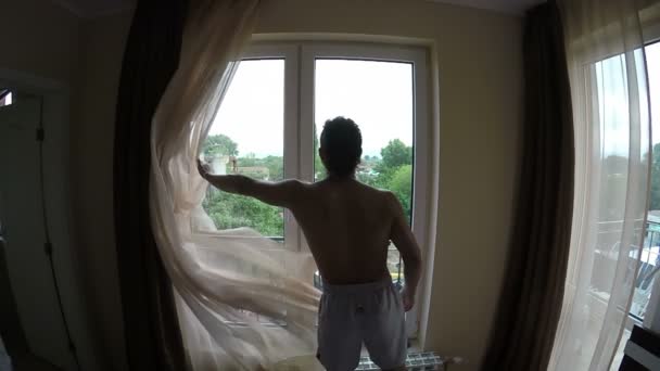 Homem Abre as Cortinas na Manhã — Vídeo de Stock
